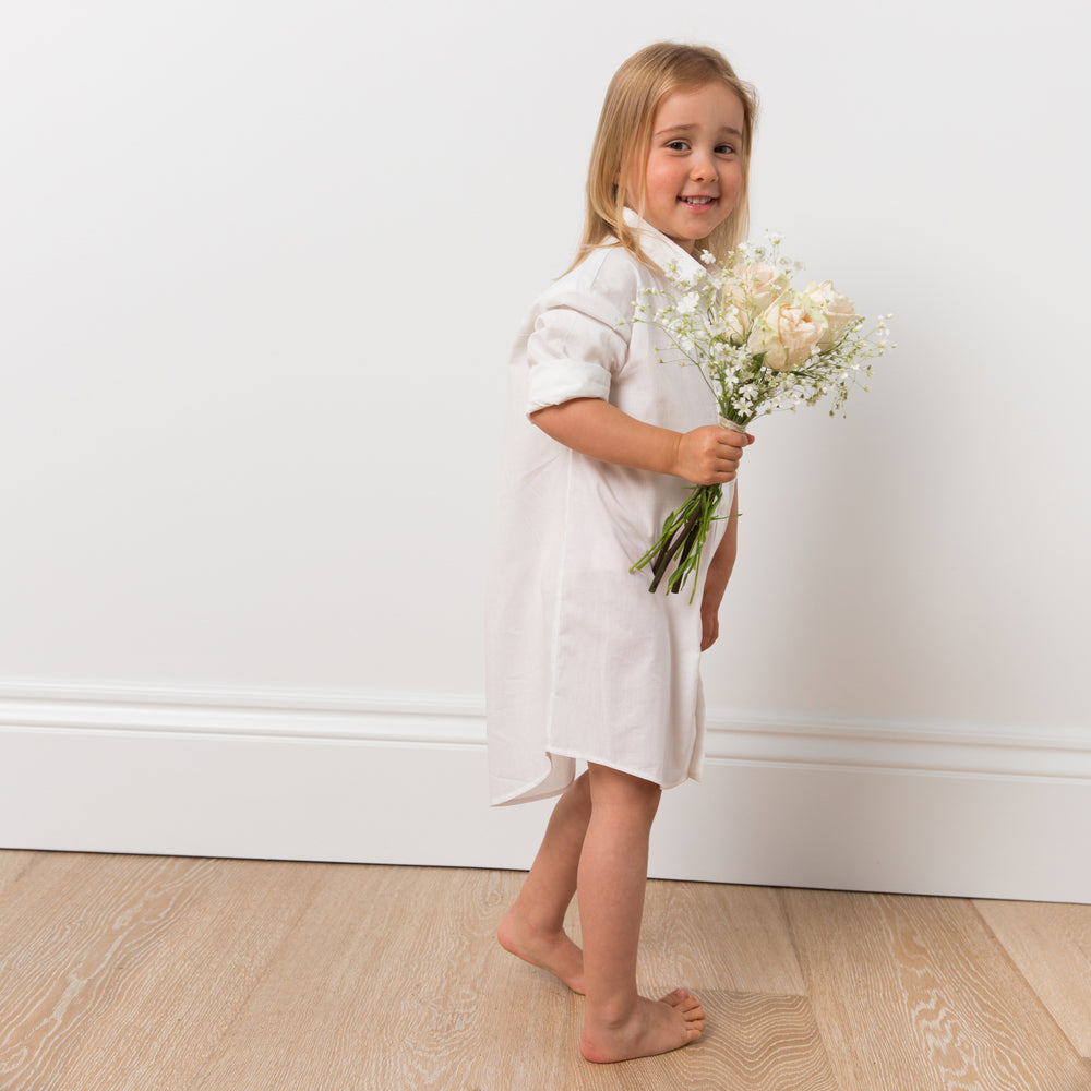 
                  
                    Girl wearing white shirt dress with flowers
                  
                