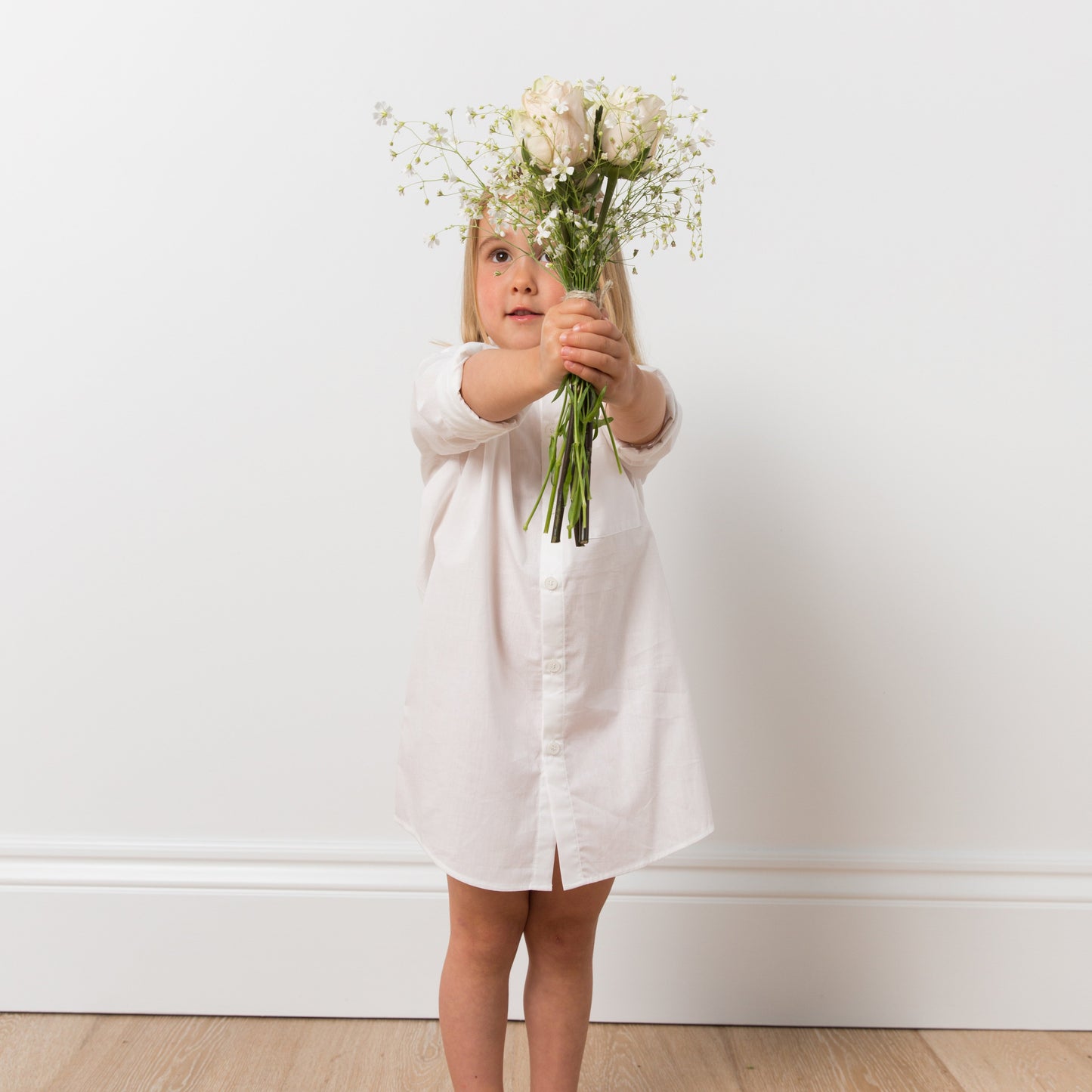 
                  
                    Girl wearing white shirt dress with flowers
                  
                