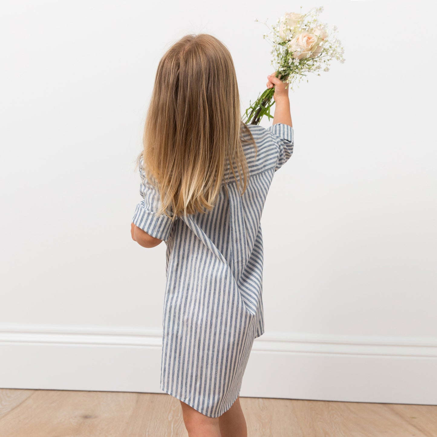
                  
                    Girl wearing striped shirt dress with flowers
                  
                